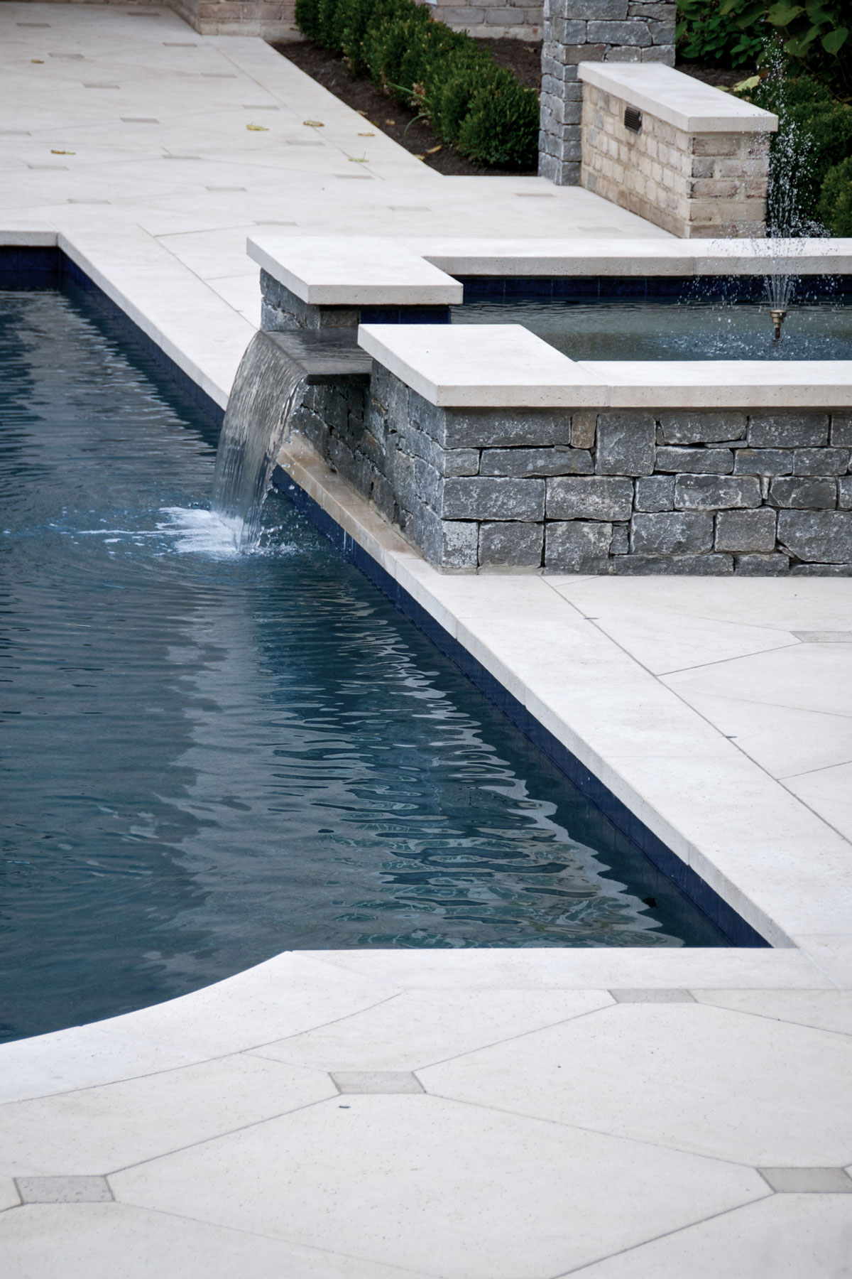 The pool deck pavers are custom fit to the nearby water feature