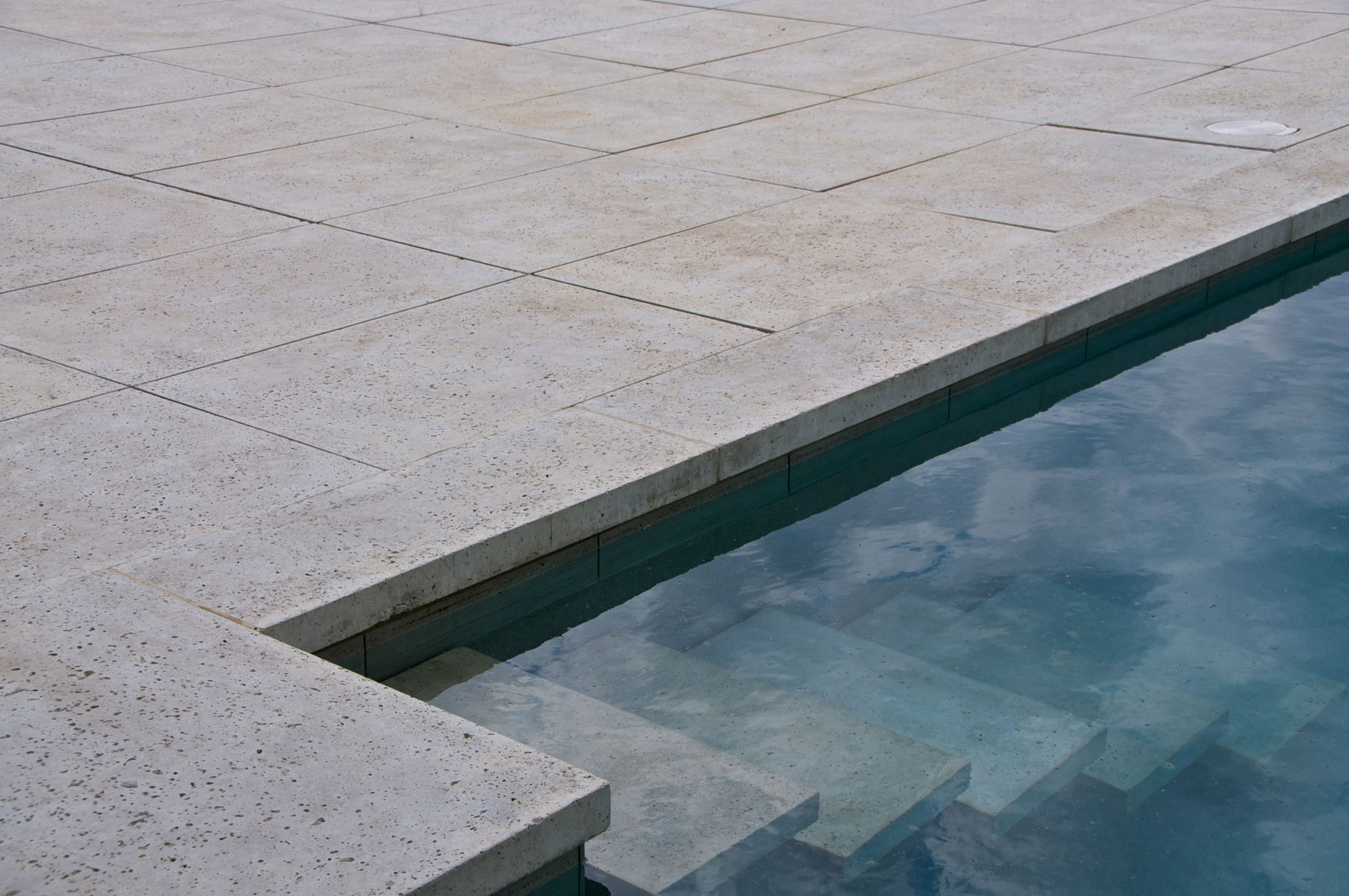The pool deck pavers transition seamlessly into the inground pool steps
