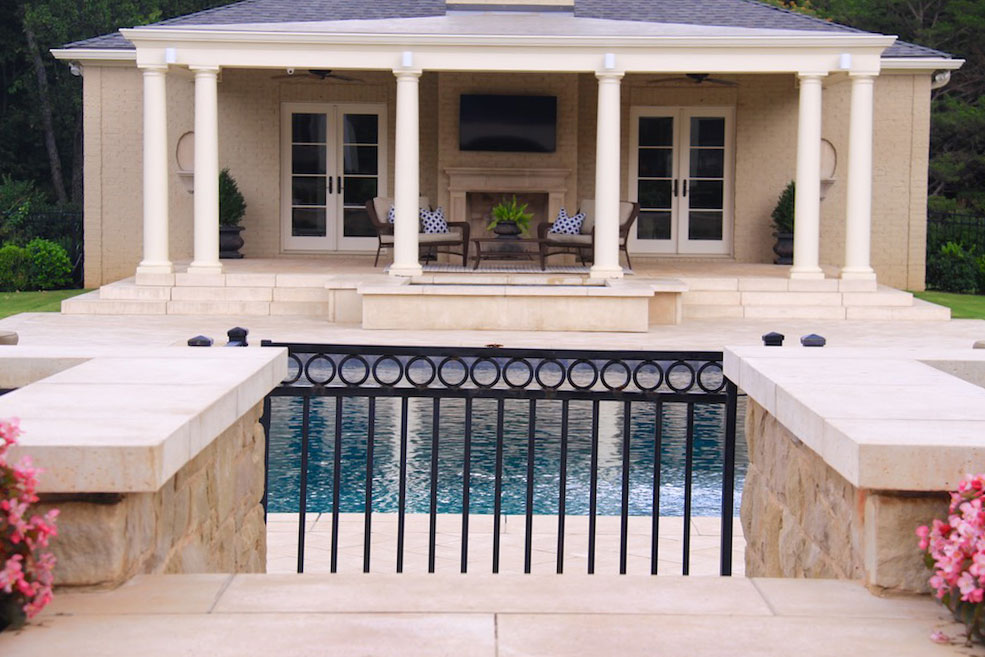 The residential patio space is enclosed in a metal fence stone pillars at the gate topped with coping tiles