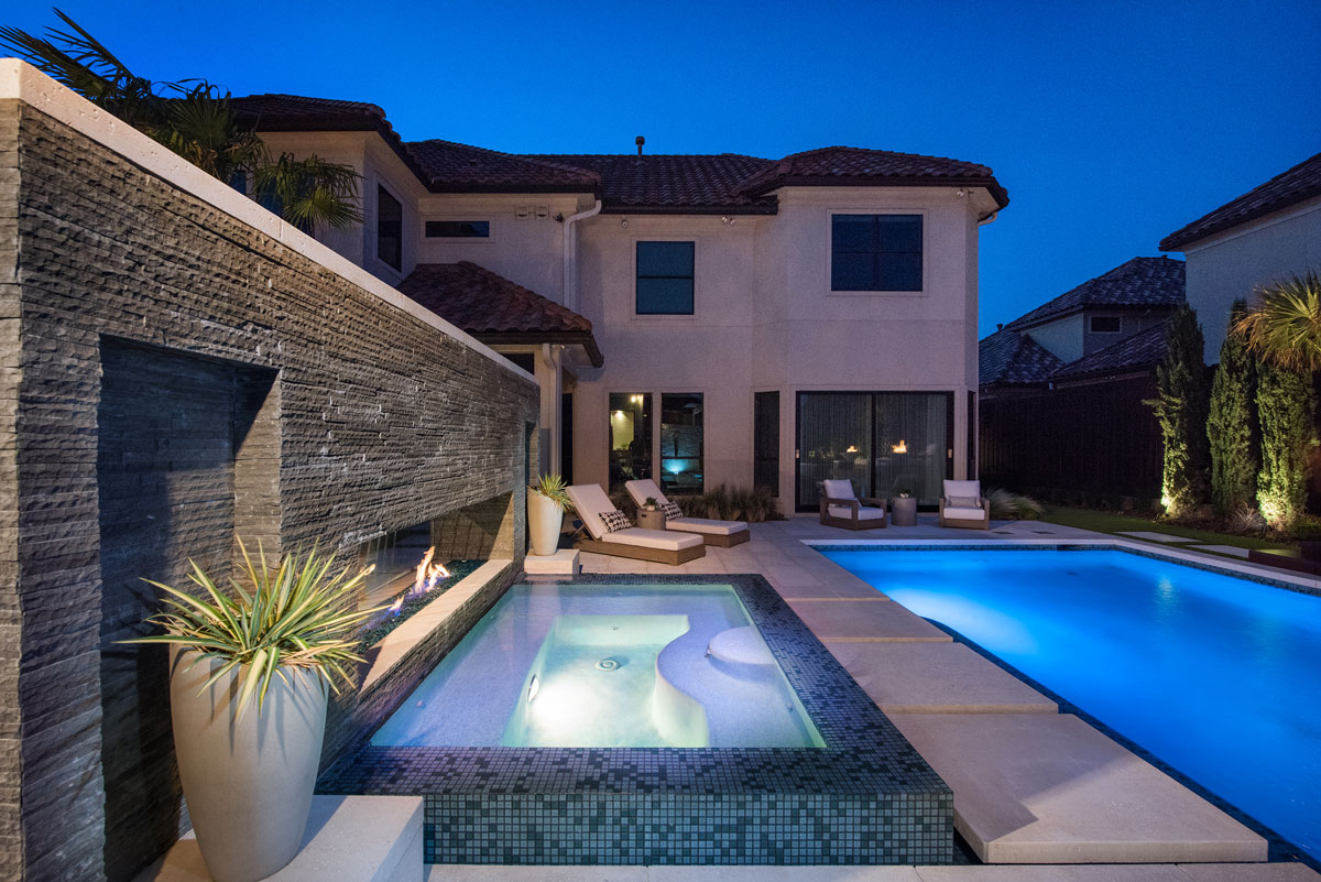 The uncovered backyard lounging pool has built-in lights for evening use
