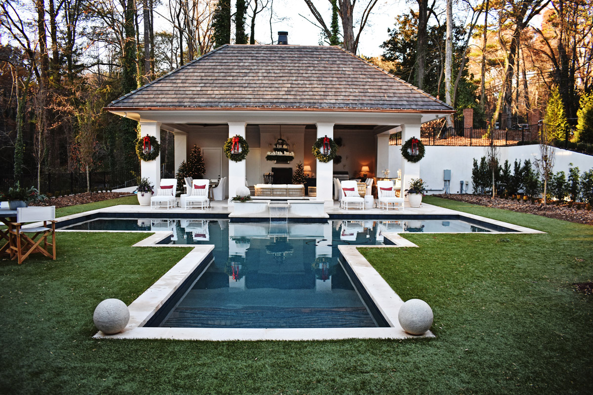 The backyard of the Holiday House Atlanta sports a pool house with large columns and Vertical Cladding